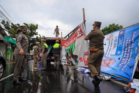 Sejumlah personel Satpol PP menertibkan alat peraga kampanye (APK) di kawasan Jalan Raya Bogor, Kramat Jati, Jakarta, Senin (29/1/2024). Foto: Iqbal Firdaus/kumparan