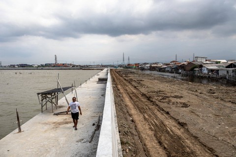 Warga berjalan di tanggul laut yang masih dalam tahap penyelesaian di kawasan Kampung Bahari Tambaklorok, Tanjung Mas, Semarang, Jawa Tengah, Kamis (1/2/2024). Foto: Aji Styawan/Antara Foto