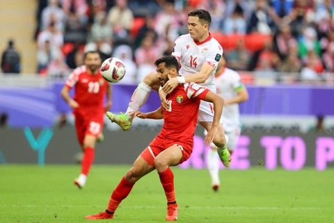 Pemain Tajikistan Alisher Shukurov beraksi bersama pemain Yordania Mousa Tamari pada Perempat Final Piala Asia di Stadion Ahmad bin Ali, Al Rayyan, Qatar, Kamis (2/2/2024). Foto: Ibraheem Al Omari/REUTERS