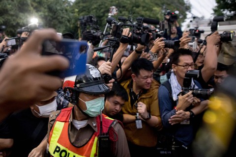Petugas polisi dan media menyaksikan mantan perdana menteri Thailand Thaksin Shinawatra tiba di kompleks keluarganya setelah dia keluar dari rumah sakit polisi di Bangkok, Thailand, Minggu (18/2/2024). Foto: Jack Taylor/AFP