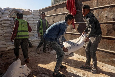 Pekerja Palestina memindahkan bantuan kemanusiaan yang masuk ke Gaza dengan truk melalui perbatasan Kerem Shalom (Karm Abu Salem) di bagian selatan wilayah Palestina pada 17 Februari 2024, di Rafah di Jalur Gaza. Foto: Said Khatib/AFP