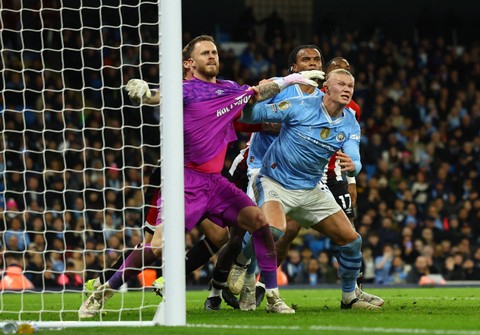 Mark Flekken duel dengan Erling Haaland saat Manchester City vs Brentford dalam laga tunda Liga Inggris 2023/24 di Stadion Etihad pada Rabu (21/2) dini hari WIB. Foto: REUTERS/Molly Darlington