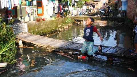 Anak-anak yang tinggal di wilayah urban memanfaatkan aliran sungai kecil sebagai hiburan untuk mandi bersama di tengah ancaman banjir saat musim hujan di Palembang, Sabtu (24/2) Foto: ary priyanto/urban id