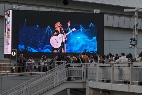 Penggemar melihat layar video besar yang mempromosikan pertunjukan penyanyi AS Taylor Swift di luar Tokyo Dome sesaat sebelum dimulainya leg pertama "Eras Tour" Asia-Pasifik di Tokyo pada 7 Februari 2024. Foto: Richard A.Brooks / AFP