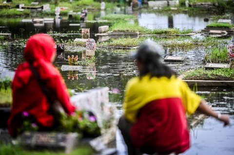 Umat Islam berdoa di depan makam keluarga dan kerabat dekat yang terendam banjir di Tempat Pemakaman Umum Semper, Jakarta, Minggu (3/3/2024). Foto: Rivan Awal Lingga/Antara Foto