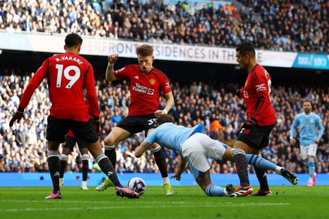 Pemain Manchester City John Stones berebut bola dengan pemain Manchester United Raphael Varane, Scott McTominay dan Casemiro pada pertandingan Liga Inggris di Stadion Etihad, Manchester, Inggris, Minggu (3/3/2024). Foto: Lee Smith/REUTERS