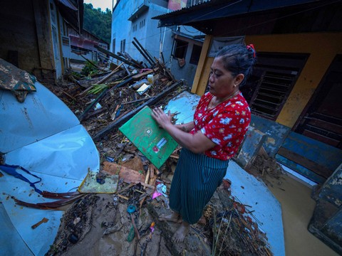 Warga membersihkan raport milik anaknya yang tertimbun material banjir bandang di Kelurahan Kasilampe, Kendari, Sulawesi Tenggara, Kamis (7/3). Foto: ANTARA FOTO/Jojon