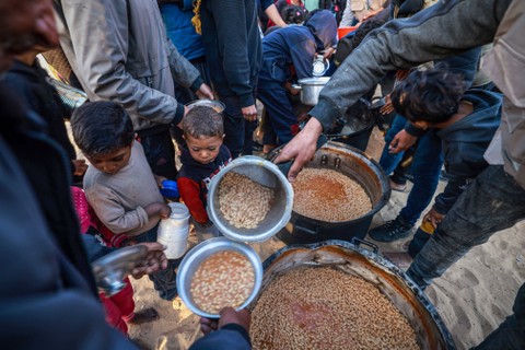 Pengungsi Palestina mengumpulkan makanan yang disumbangkan oleh sebuah badan amal sebelum berbuka puasa, pada hari pertama bulan suci Ramadhan, di Rafah di Jalur Gaza selatan pada 11 Maret 2024. Foto: Mohammed Abed / AFP