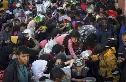 Pengungsi Palestina mengumpulkan makanan yang disumbangkan oleh sebuah badan amal sebelum berbuka puasa, pada hari pertama bulan suci Ramadhan di Rafah, di Jalur Gaza selatan pada 11 Maret 2024. Foto: AFP