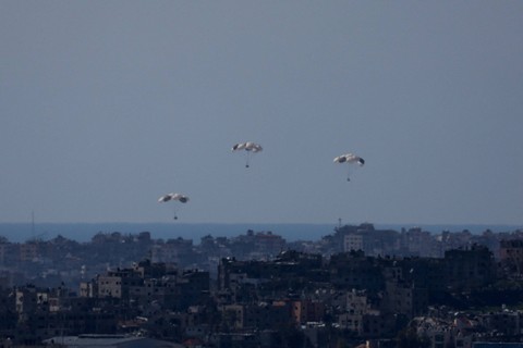 Paket bantuan jatuh ke arah Gaza utara, setelah dijatuhkan dari pesawat militer, di tengah konflik Israel dan Hamas, terlihat dari perbatasan Israel dengan Gaza, di Israel selatan, Senin (11/3/2024). Foto: Ronen Zvulun/REUTERS