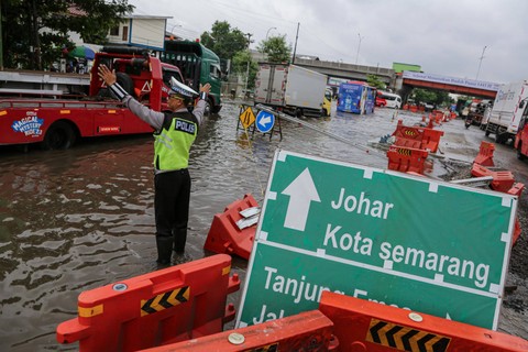 Polis mengatur lalu lintas kendaraan yang macet akibat banjir yang merendam jalur pantura di Jalan Kaligawe Raya, Semarang, Jawa Tengah, Rabu (13/3/2024). Foto: Makna Zaezar/ANTARA FOTO