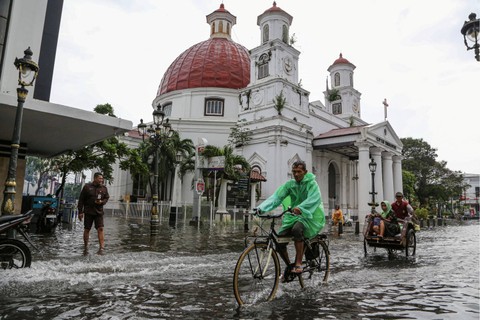Warga mengayuh sepeda dan becak untuk menembus banjir yang merendam di ruas jalan GPIB Immanuel (Gereja Bleduk) kawasan Cagar Budaya Nasional Kota Lama Semarang, Jawa Tengah, Kamis (14/3/2024). Foto: Makna Zaezar/Antara Foto