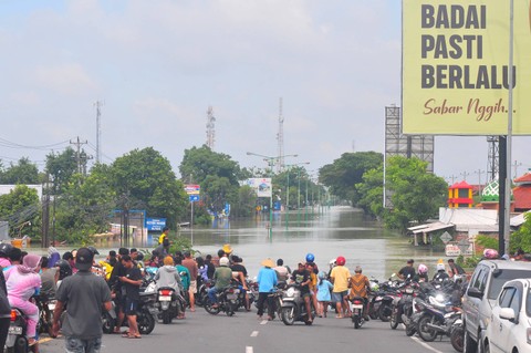 Warga menyaksikan jalan Pantura yang terendam banjir di Karanganyar, Demak, Jawa Tengah, Minggu (17/3/2024). Foto: Yusuf Nugroho/Antara Foto