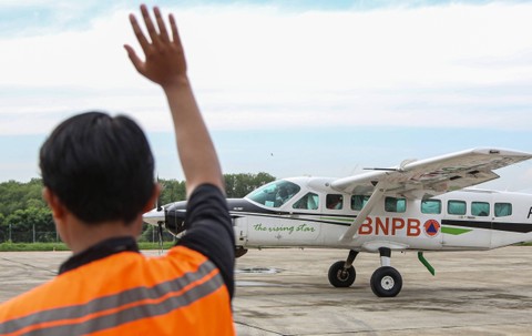 Petugas melambaikan tangan kepada pilot pesawat Cessna 208B Grand Caravan EX yang akan terbang membawa persemaian garam untuk Teknologi Modifikasi Cuaca (TMC) di Bandara Internasional Ahmad Yani, Semarang, Jawa Tengah, Senin (18/3/2024). Foto: Makna Zaezar/Antara Foto