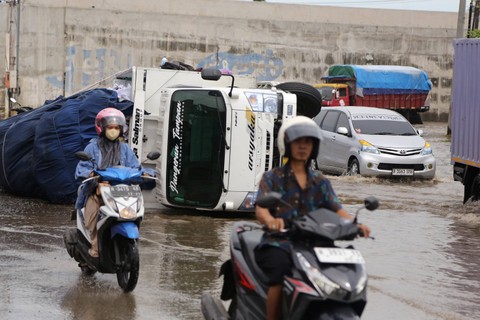 Sejumlah kendaraan melintas divdekat truk yang terguling di jalur pantura pascabanjir yang merendam kawasan Jalan Kaligawe Raya-Genuk, Semarang, Jawa Tengah, Senin (18/3/2024). Foto: Makna Zaezar/ANTARA FOTO