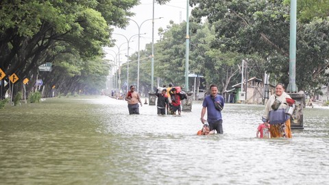 Sejumlah warga melintasi jalan yang terendam banjir di Jalur Pantura Demak-Kudus, Karanganyar, Demak, Jawa Tengah, Kamis (21/03/2024). Foto: Dicky Adam Sidiq/kumparan