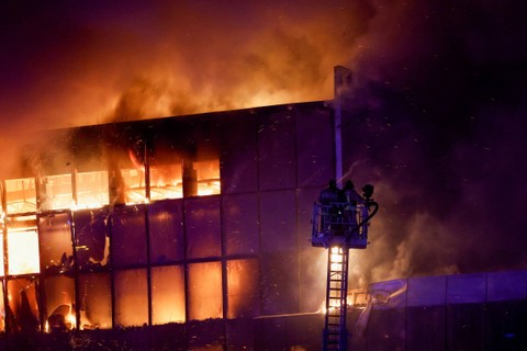 Tim penyelamat bekerja untuk memadamkan api di tempat konser Balai Kota Crocus yang terbakar setelah insiden penembakan, di luar Moskow, Rusia, Jumat (22/3/2024). Foto: Maxim Shemetov/REUTERS