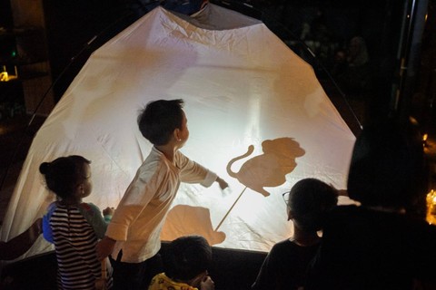 Permainan wayang tenda dengan sorot lampu petromax.