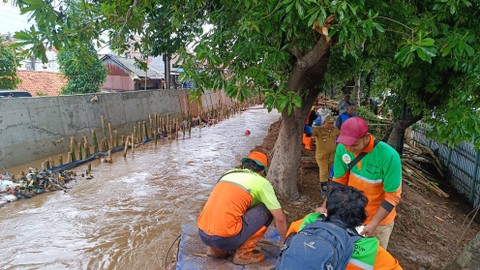 Petugas memperbaiki tanggul sungai yang jebol di Hek Kramat Jati, Jakarta, Senin (25/3/2024). Foto: Thomas Bosco/kumparan