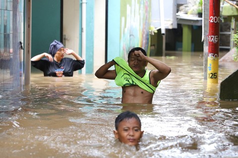 Warga melintasi banjir yang merendam kawasan Kebon Pala, Jakarta Timur, Senin (25/3/2024). Foto: Iqbal Firdaus/kumparan