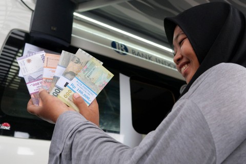 Warga menunjukkan uang pecahan baru saat layanan penukaran uang dari mobil kas keliling Bank Indonesia di Pasar Badung, Denpasar, Bali, Senin (25/3/2024). Foto: Nyoman Hendra Wibowo/ANTARA FOTO