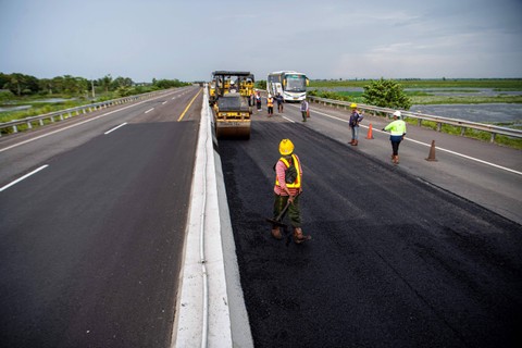Pekerja dibantu alat berat menyelesaikan pengaspalan Jalan Tol Trans Sumatera ruas Kayu Agung-Palembang (Kapal) di Jejawi, Ogan Komering Ilir (OKI), Sumatera Selatan, Senin (27/3/2023). Foto: Nova Wahyudi/ANTARA FOTO