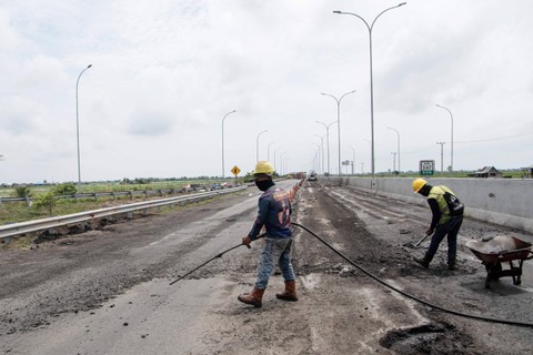 Pekerja dibantu alat berat menyelesaikan pengaspalan Jalan Tol Trans Sumatera ruas Kayu Agung-Palembang (Kapal) di Jejawi, Ogan Komering Ilir (OKI), Sumatera Selatan, Senin (27/3/2023). Foto: Nova Wahyudi/ANTARA FOTO