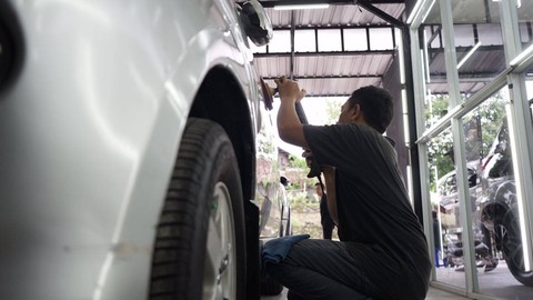 Seorang pekerja sedang memoles mobil pelanggan. Foto: Arif UT/Pandangan Jogja
