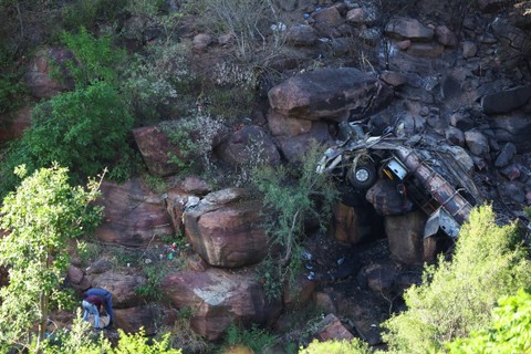 Petugas polisi mengumpulkan pakaian di dekat sisa-sisa bus yang terbakar yang membawa peziarah Paskah dari Botswana ke Moria, menyusul kecelakaannya di dekat Mamatlakala di provinsi utara Limpopo, Afrika Selatan, Jumat (29/3/2024). Foto: Siphiwe Sibeko/REUTERS