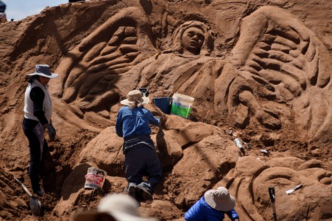 Seniman membuat patung pasir yang mewakili gairah, kematian dan kebangkitan Yesus Kristus selama perayaan Pekan Suci  di Arenal de Cochiraya, di pinggiran Oruro, Bolivia (29/3/2024). Foto: REUTERS/Claudia Morales