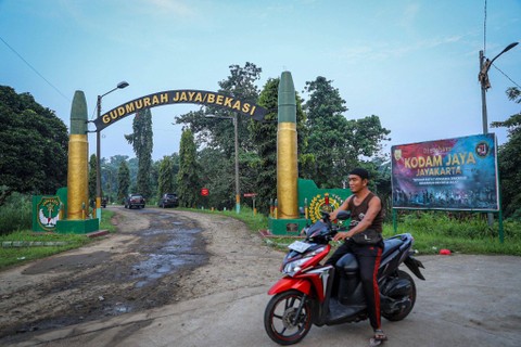 Warga melintas di depan gerbang Gudang amunisi Daerah (Gudmurah) Jaya/Bekasi, Ciangsana, Kabupaten Bogor, Jawa Barat, Minggu (30/3/2024). Foto: Iqbal Firdaus/kumparan