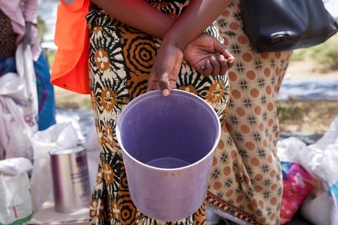 Seorang wanita memegang ember kosong sambil menunggu untuk menerima bantuan makanan dalam antrean di distrik Mangwe di barat daya Zimbabwe, Jumat, (22/3/2024) Foto: Tsvangirayi Mukwazhi/AP Photo