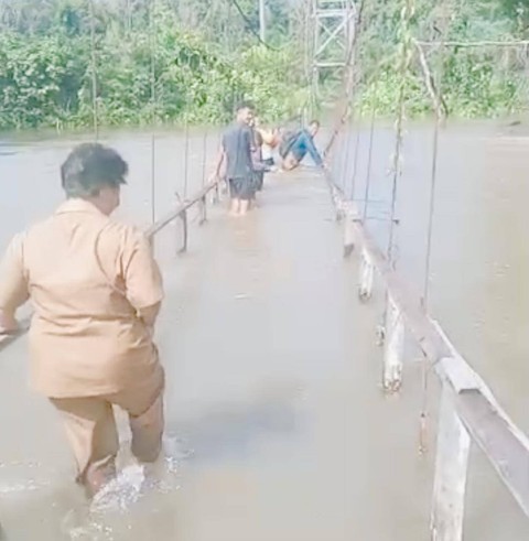 Guru di SDN 21 Jering, Landak harus melewati jembatan rusak yang terendam banjir. Foto: Dok. Instagram @kamidayakkalbar
