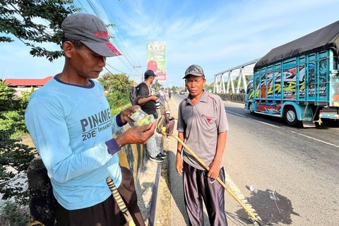 Warga penyapu koin saat menunggu dan berebut koin di tengah jalan Pantura saat mudik Lebaran 2024, Jumat (5/4/2024). Foto: Panji Asmara/kumparan