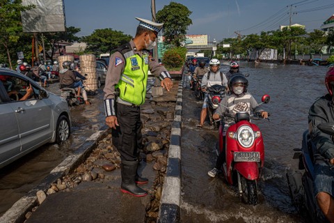 Petugas kepolisian mengatur arus lalu lintas yang tersendat karena banjir menggenangi jalur utama pantura Semarang-Surabaya di Jalan Kaligawe Raya, Kota Semarang, Jawa Tengah, Sabtu (6/4/2024). Foto: Aji Styawan/ANTARA FOTO 
