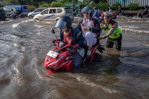 Petugas kepolisian membantu mendorong sepeda motor warga yang mogok seusai menembus banjir di jalur utama pantura Semarang-Surabaya, Jalan Kaligawe Raya, Kota Semarang, Jawa Tengah, Sabtu (6/4/2024). Foto: Aji Styawan/ANTARA FOTO 