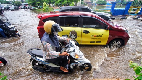 Seorang pengendara motor menerobos banjir akibat hujan dengan intensitas tinggi yang melanda Kota Palembang, Minggu (7/4) Foto: ary priyanto/urban id