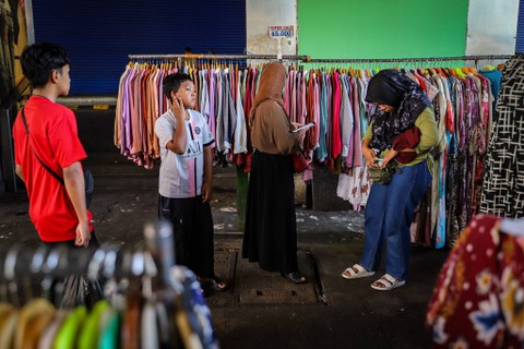 Pengunjung memilih pakaian di lapak pedagang di kawasan trotoar depan Blok A Pasar Tanah Abang di Jakarta, Jumat (12/4/2024). Foto: Iqbal Firdaus/kumparan