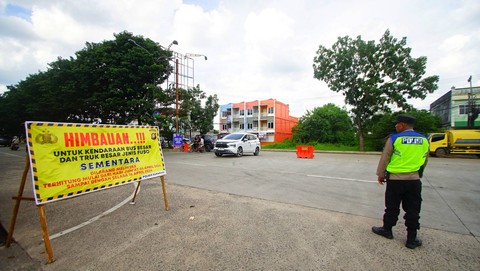 Petugas kepolisian berjaga di depan terminal di samping spanduk berisi pelarangan melintas bagi kendaraan truk demi menghindari kemacetan, Minggu (14/4) Foto: ary priyanto/urban id