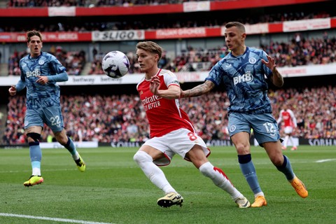 Pemain Arsenal Martin Odegaard berebut bola dengan pemain Aston Villa Lucas Digne pada pertandingan lanjutan Liga Inggris di Stadion Emirates, London, Inggris, Minggu (14/4/2024). Foto: David Klein/ REUTERS
