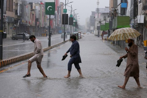 Orang-orang menyeberang jalan saat hujan lebat di Peshawar, Pakistan, Senin, (15/4/2024) Foto: Muhammad Sajjad/AP