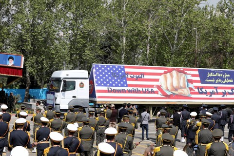 Sebuah truk militer Iran membawa tanda anti-AS ketika para petugas berdiri selama parade militer sebagai bagian dari upacara memperingati hari militer tahunan negara itu di ibu kota Teheran, Iran, Rabu (17/4/2024). Foto: Atta Kenare/AFP