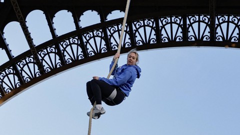 Atlet Prancis Anouk Garnier melakukan pemanasan sebelum memanjat tali Menara Eiffel untuk memecahkan rekor dunia, di Menara Eiffel di Paris, pada 10 April 2024. Foto: STEPHANE DE SAKUTIN / AFP