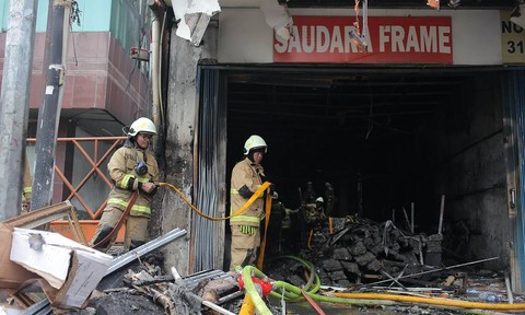 Petugas pemadam kebakaran melakukan pendinginan ruko Saudara Frame dan Galery yang terbakar di Jalan Mampang Prapatan, Jakarta, Jumat (19/4/2024). Foto: Reno Esnir/Antara Foto