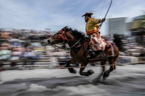 Seorang pemanah berseragam prajurit samurai kuno menunggangi kuda sambil menembakkan panah ke sasaran selama demonstrasi seni bela diri samurai menunggang kuda Yabusame di Taman Sumida di Tokyo (20/4/2024) Foto: YUICHI YAMAZAKI/AFP