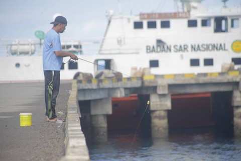 Seorang warga memancing di Pelabuhan Tagulandang yang pada erupsi Gunung Ruang terkena banyak patu pijar dan pasir. (foto: febry kodongan/manadobacirita)