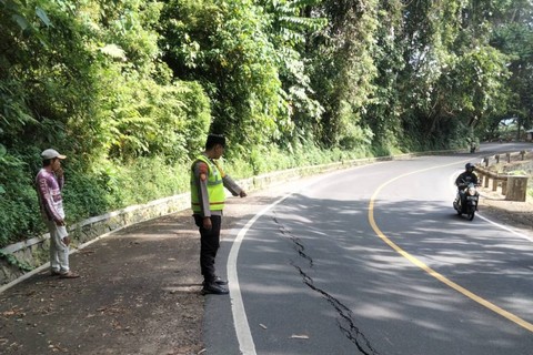 Polisi meninjau kondisi jalan yang mengalami retakan di Jalur Gumitir. Foto: Mili.id