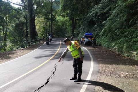 Polisi meninjau kondisi jalan yang mengalami retakan di Jalur Gumitir. Foto: Mili.id