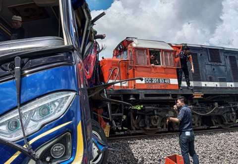 Petugas berusaha mengevakuasi bus penumpang Putra Sulung yang tertabrak kereta api Rajabasa di perlintasan tanpa palang pintu di Jalan Pertanian, Kecamatan Martapura, Kabupaten OKU Timur, Sumatera Selatan, Minggu (21/4/2024). Foto: T Fikri W/Antara