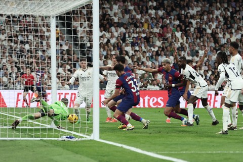 Momen saat sepintas bola telah melewati gawang yang dijaga Andriy Lunin saat Real Madrid vs Barcelona dalam laga lanjutan Liga Spanyol 2023/24 di Estadio Santiago Bernabeu pada Senin (22/4) dini hari WIB. Foto: AFP/THOMAS COEX